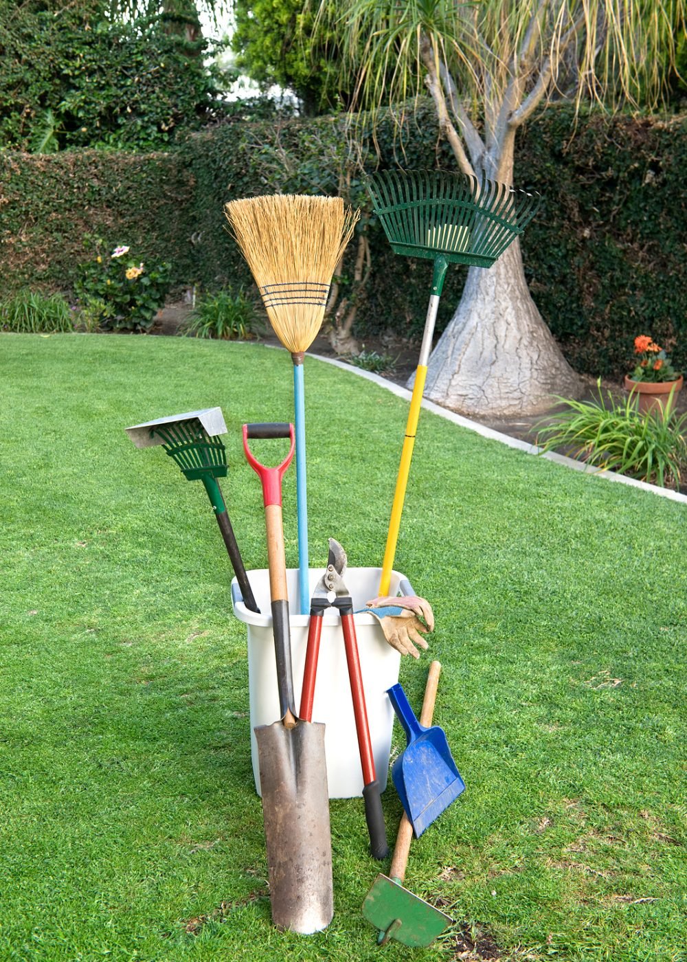 Yard working and gardening tools on green grass and a well groomed yard.